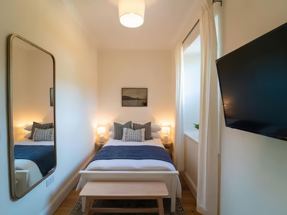 A bedroom with a bed, television, and mirror at Foundry Farm Apartment