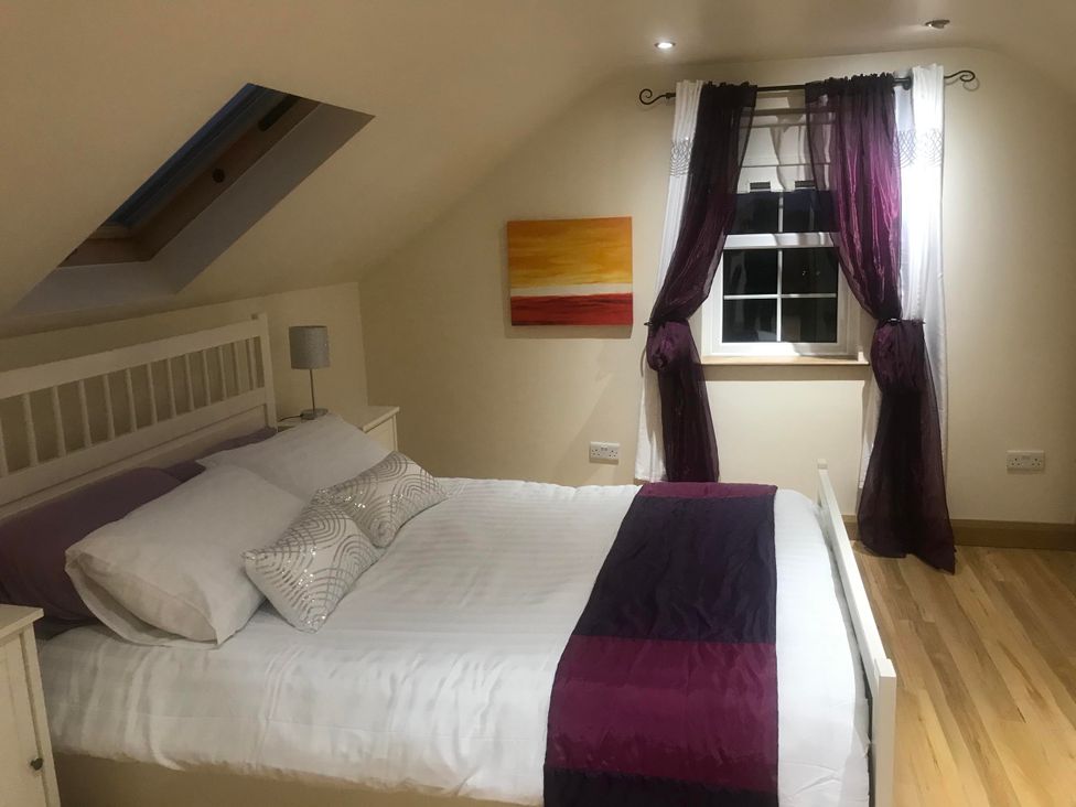 A bedroom with a bed, lamp, curtains and painting at Dungannon 2 Bed Bungalow - Sleeps 5 - Pet Friendly near Dungannon
