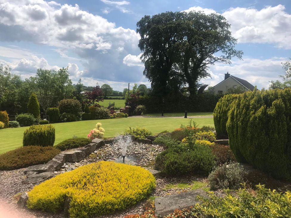 A garden with a fountain and flower beds at Dungannon 2 Bed Bungalow - Sleeps 5 - Pet Friendly near Dungannon