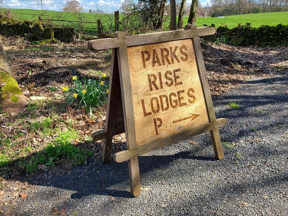A wooden sign pointing to Parks Rise Lodges with a gravel pathway near Hay-On-Wye
