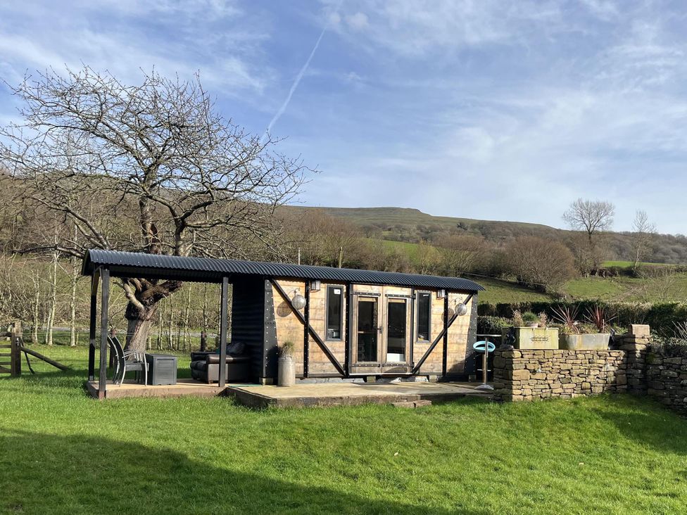 A garden area with a shed and tree at Transformed Railway Wagon- Sleeps2-Garden-Firepit Powys near Crickhowell