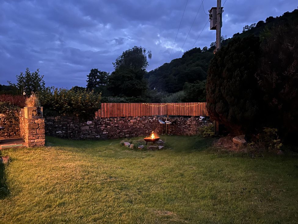 An outdoor space with a fire pit and stone wall at Transformed Railway Wagon- Sleeps2-Garden-Firepit near Crickhowell