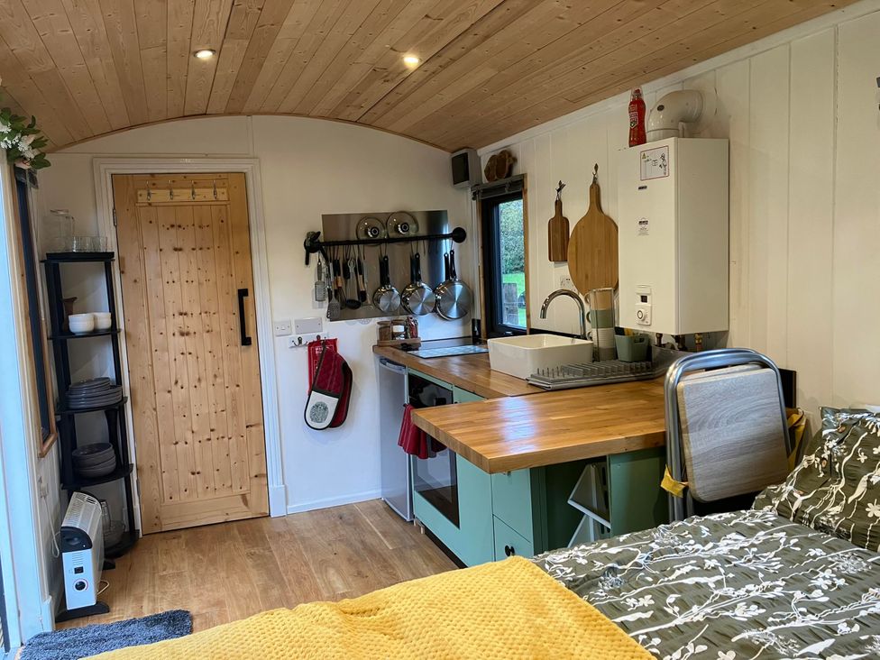 A kitchen with a sink, stove, and refrigerator at Transformed Railway Wagon- Sleeps2-Garden-Firepit in Powys near Crickhowell