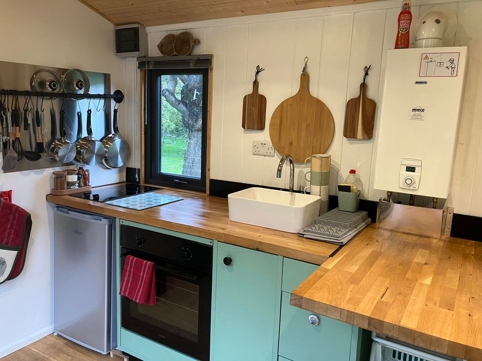 A kitchen with a sink, cooker and countertop at Transformed Railway Wagon- Sleeps2-Garden-Firepit in Powys near Crickhowell