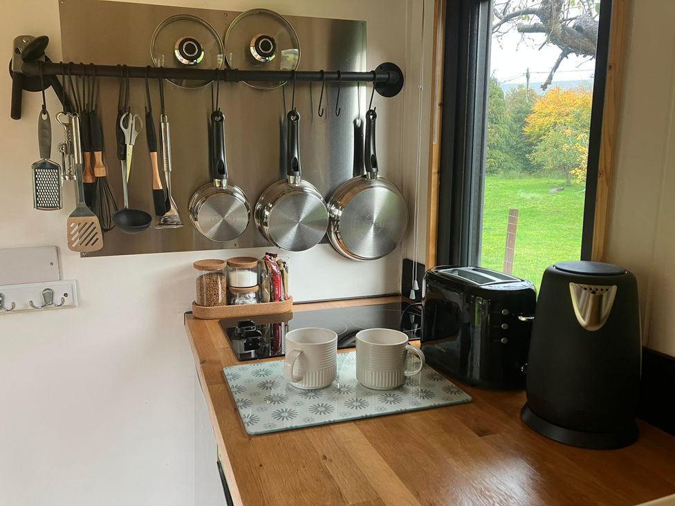 A kitchen with pots on the wall and mugs on a countertop at Transformed Railway Wagon- Sleeps2-Garden-Firepit in Powys near Crickhowell