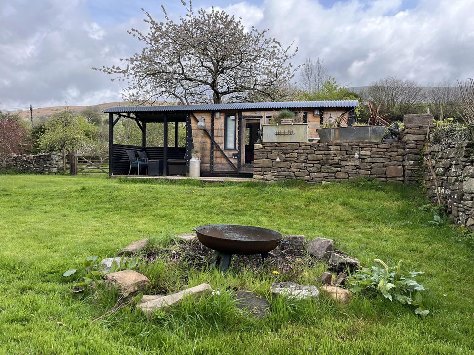 A garden with a firepit and a building at Transformed Railway Wagon- Sleeps2-Garden-Firepit near Crickhowell