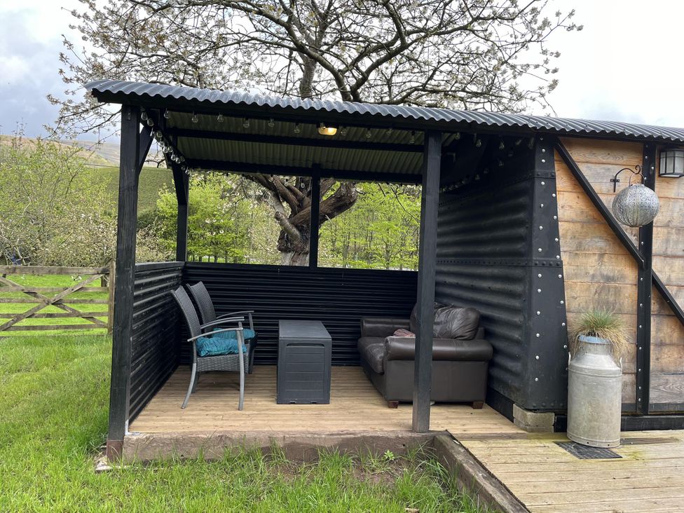 An outdoor seating area with a sofa and chairs at Transformed Railway Wagon- Sleeps2-Garden-Firepit in Powys near Crickhowell