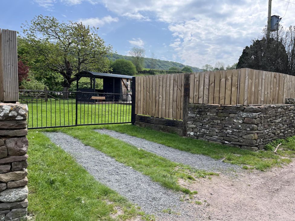 A garden with a gravel path and a wooden gate at Transformed Railway Wagon- Sleeps2-Garden-Firepit near Powys near Crickhowell