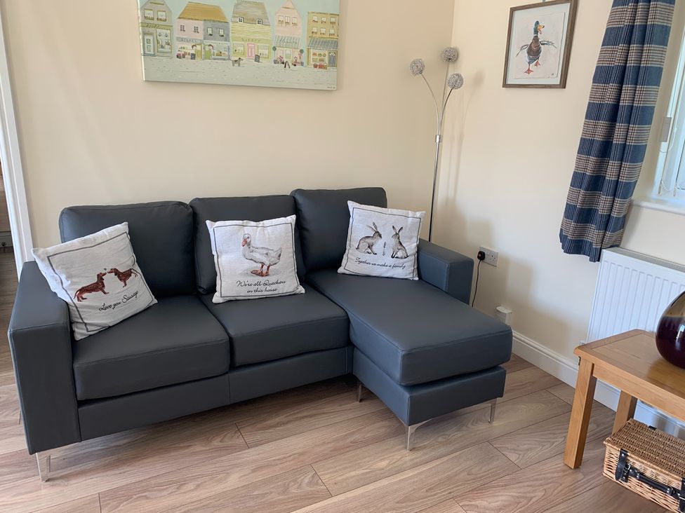 A living room with a sofa and cushions at TBC
