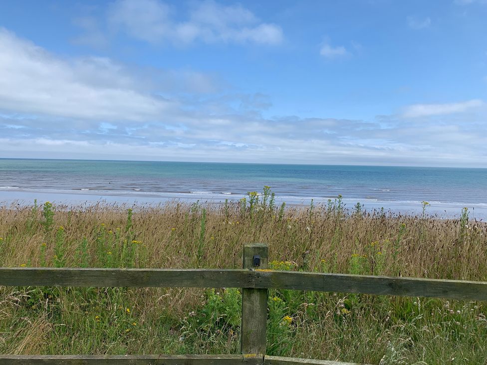 A view of the sea with grass and a wooden fence at TBC 