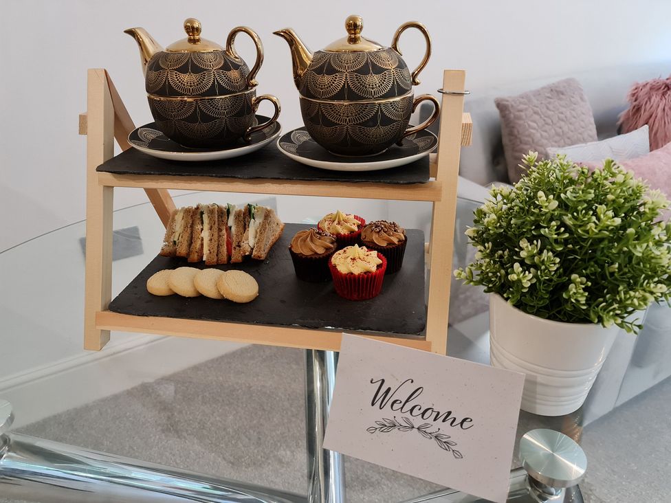 A serving tray with teapots, sandwiches, cookies, cupcakes and a welcome sign at TBC in 