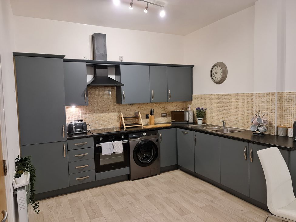 A kitchen with cabinets, stove, washing machine, and sink at TBC