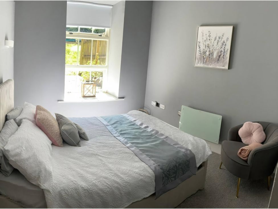A bedroom with a bed, chair, and window at TBC 