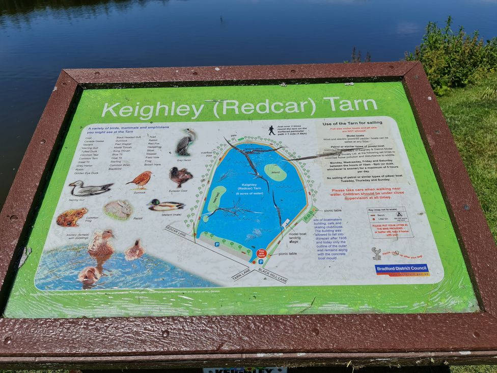 An information board with a map of Keighley Tarn and local wildlife at TBC