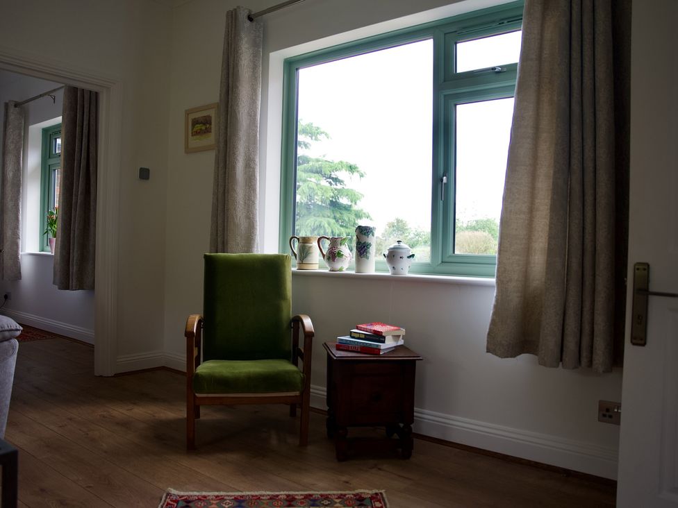 A living room with a green chair and window at TBC