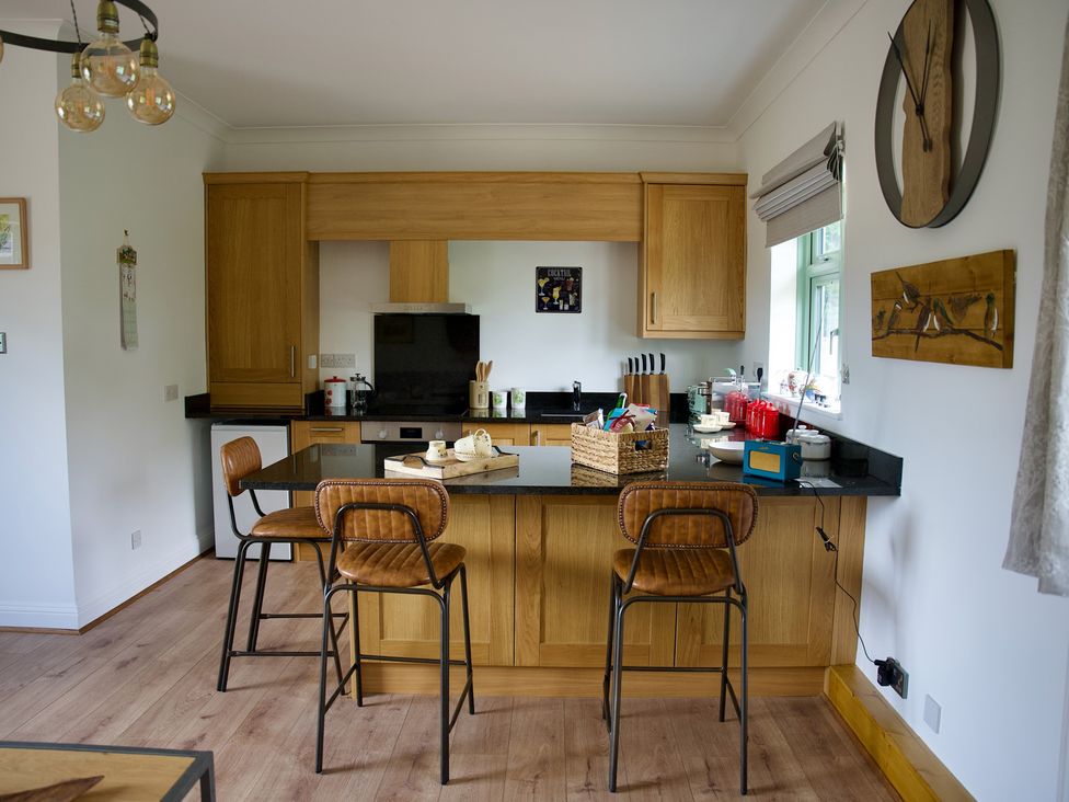 A kitchen with wooden cabinets and bar stools at TBC