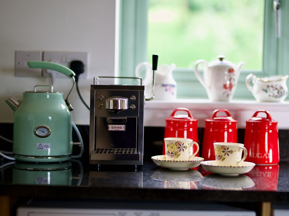 A kettle and espresso machine with coffee cups and teapots in a kitchen at TBC 