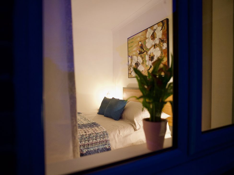 A bedroom with a bed and plant viewed from a window at TBC