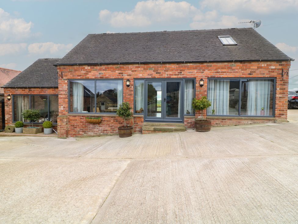 A brick exterior with large windows and planters at The Croft, Home Farm Ripley