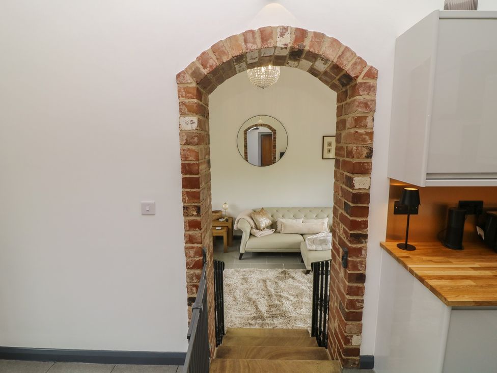 A living room with a sofa and mirror visible from a staircase at The Croft, Home Farm in Ripley