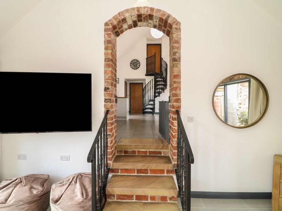 A hallway with stairs and a brick arch at The Croft, Home Farm in Ripley