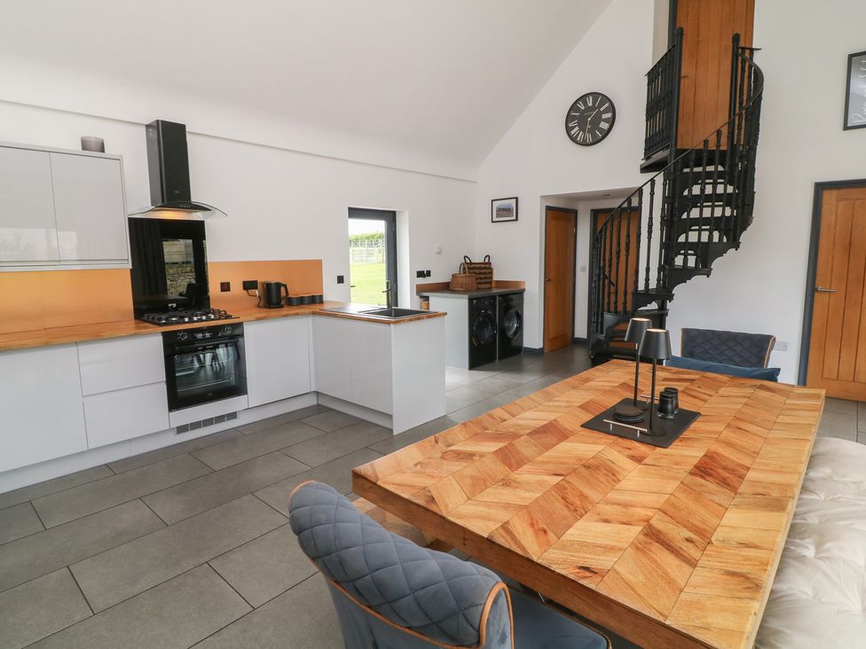 A kitchen with a dining table and spiral staircase at The Croft, Home Farm Ripley