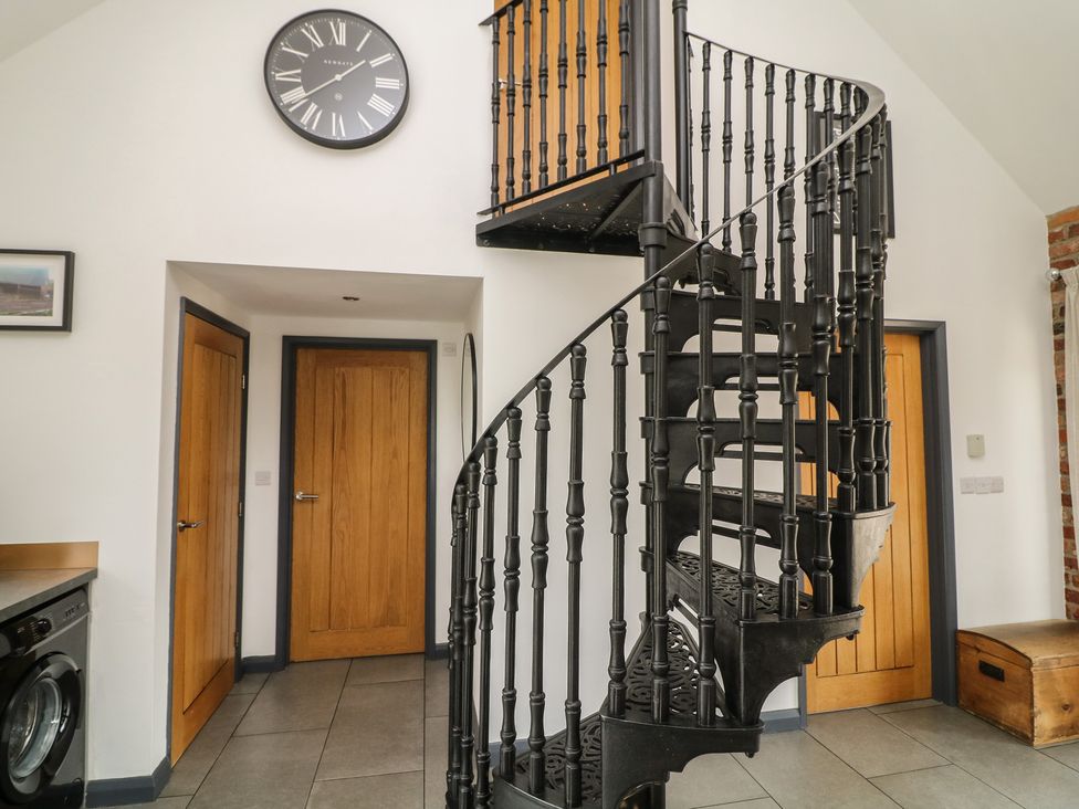 A hallway featuring a spiral staircase and a washing machine at The Croft, Home Farm, Ripley