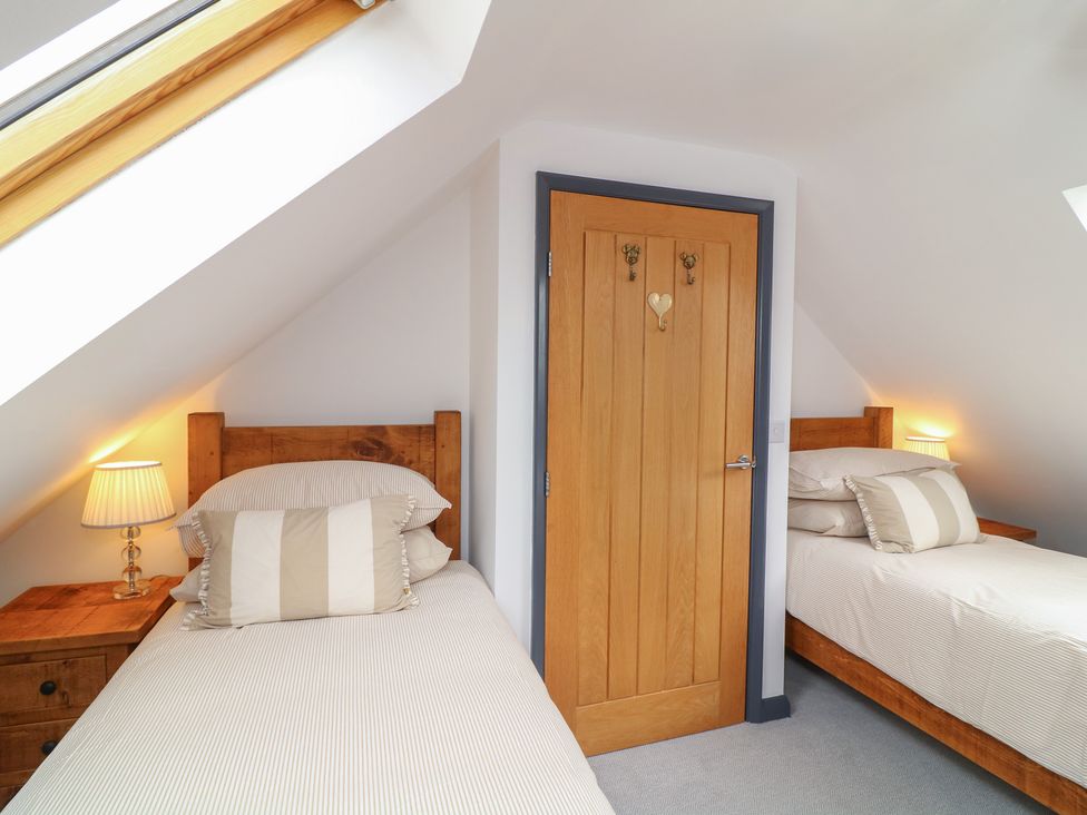A bedroom with twin beds and wooden door at The Croft, Home Farm, Ripley