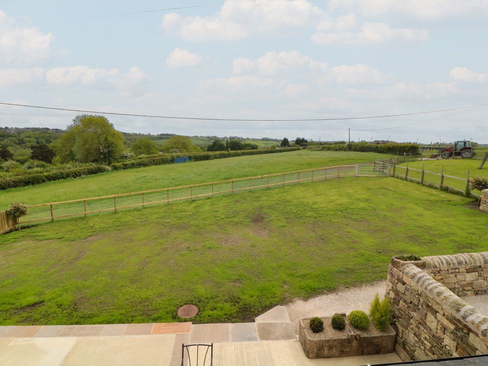 A view of a grassy area with a fence and tractor at The Croft, Home Farm in Ripley