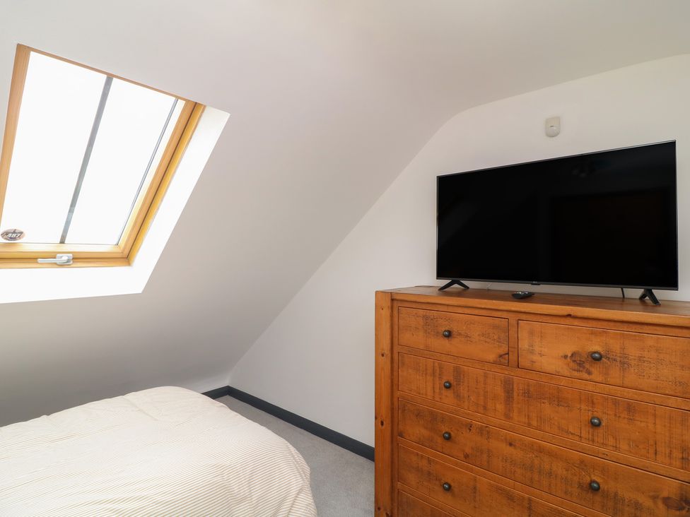 A bedroom with a window and television on a chest of drawers at The Croft, Home Farm in Ripley