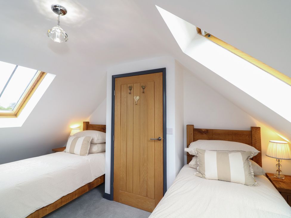 A bedroom with two single beds and a window at The Croft, Home Farm in Ripley