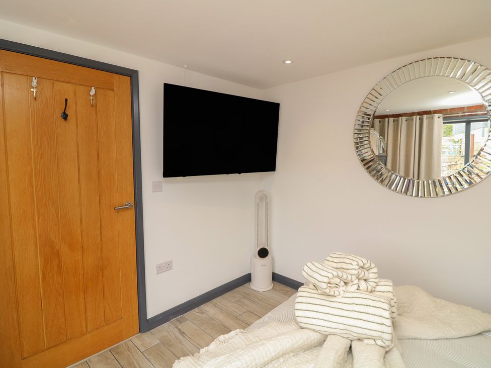 A bedroom with a TV and door at The Croft, Home Farm Ripley