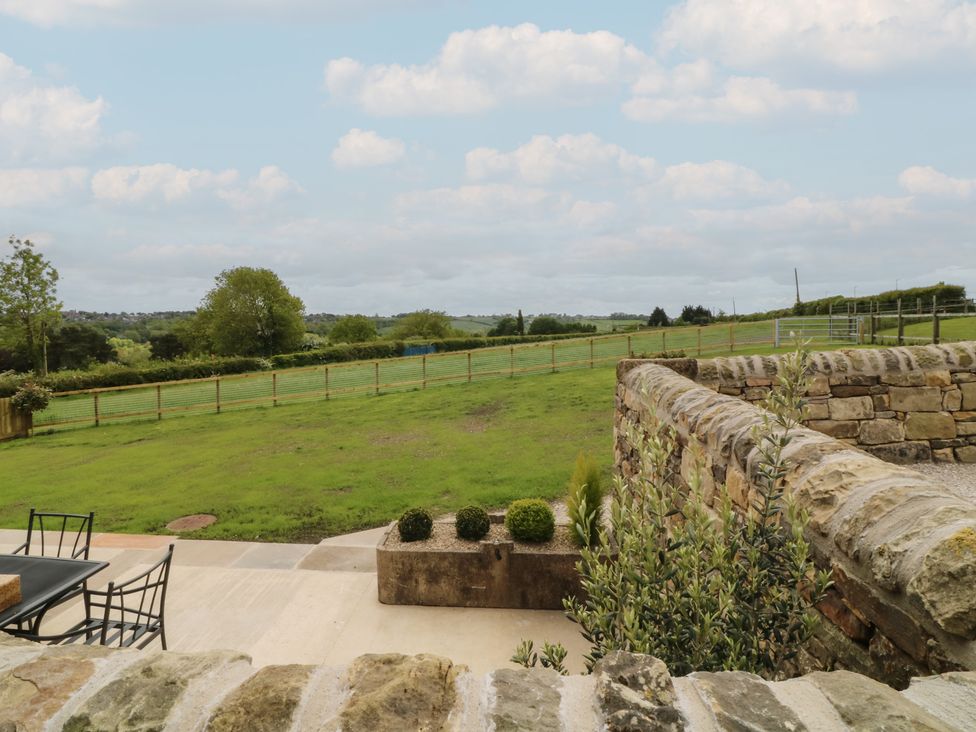 An outdoor area with a stone wall and furniture at The Croft, Home Farm Ripley