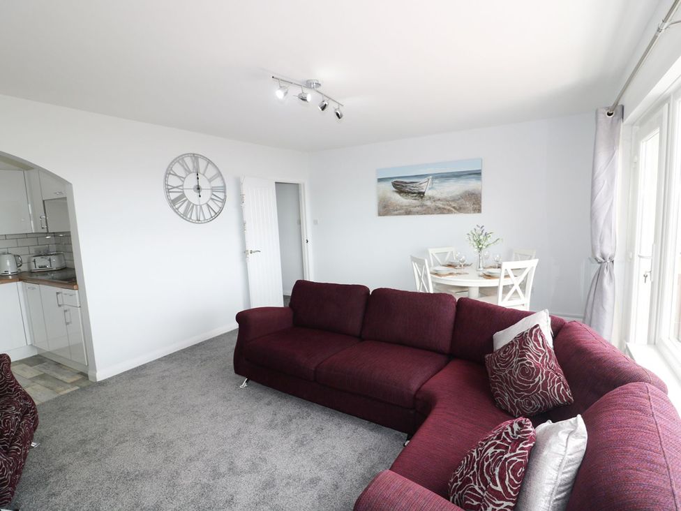 A living room with a sofa and dining area at The Cartwheel in Amroth