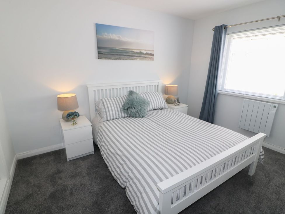 A bedroom with a bed and nightstand at The Cartwheel in Amroth