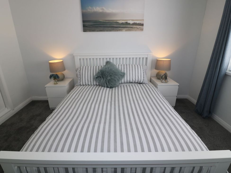 A bedroom with a striped bed and bedside tables at The Cartwheel in Amroth