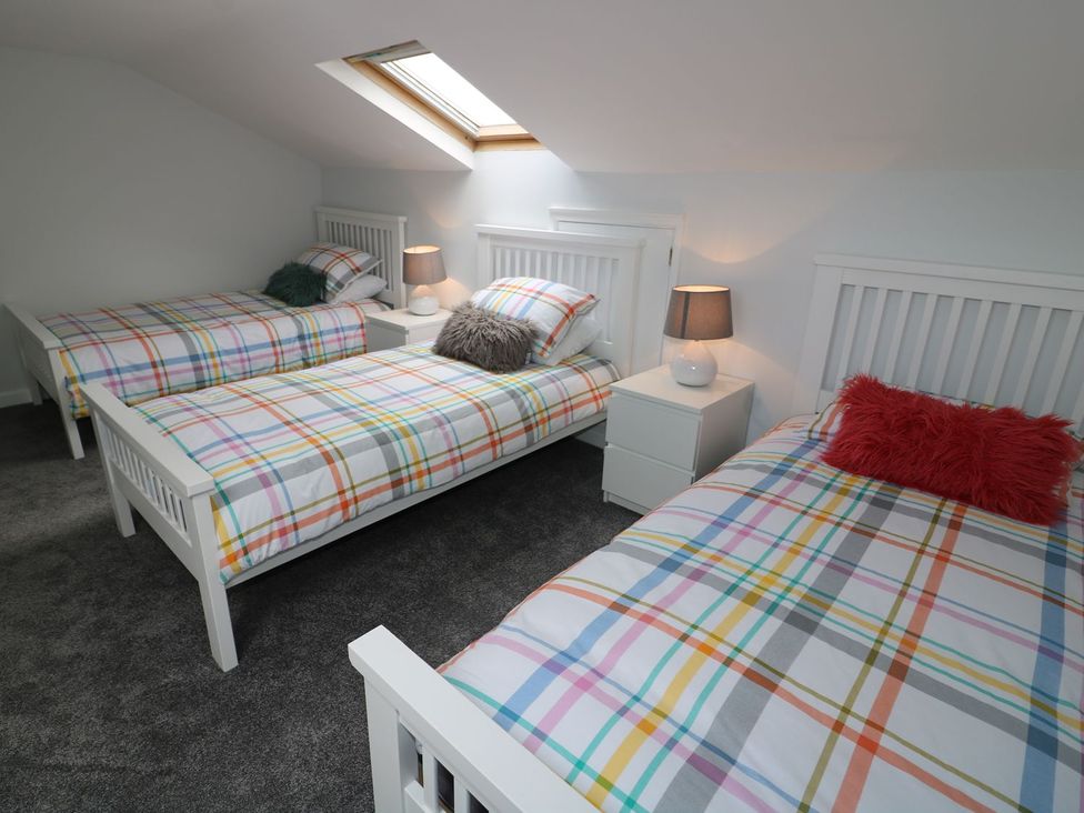 A bedroom with three beds and lamps at The Cartwheel in Amroth
