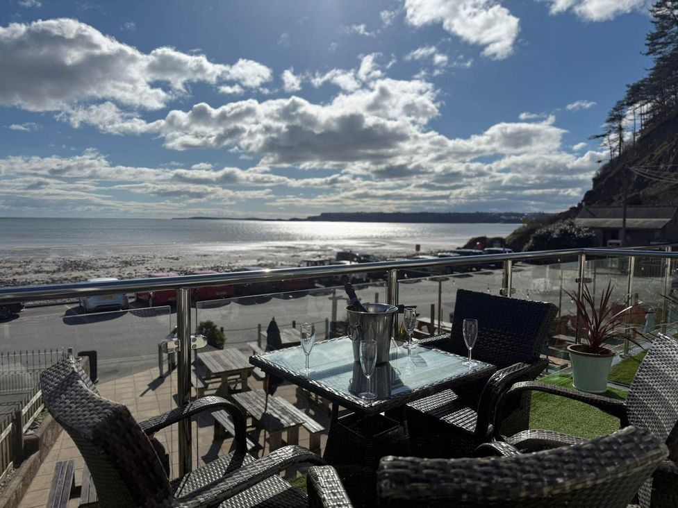 An outdoor seating area with table and chairs overlooking the beach at The Cartwheel in Amroth