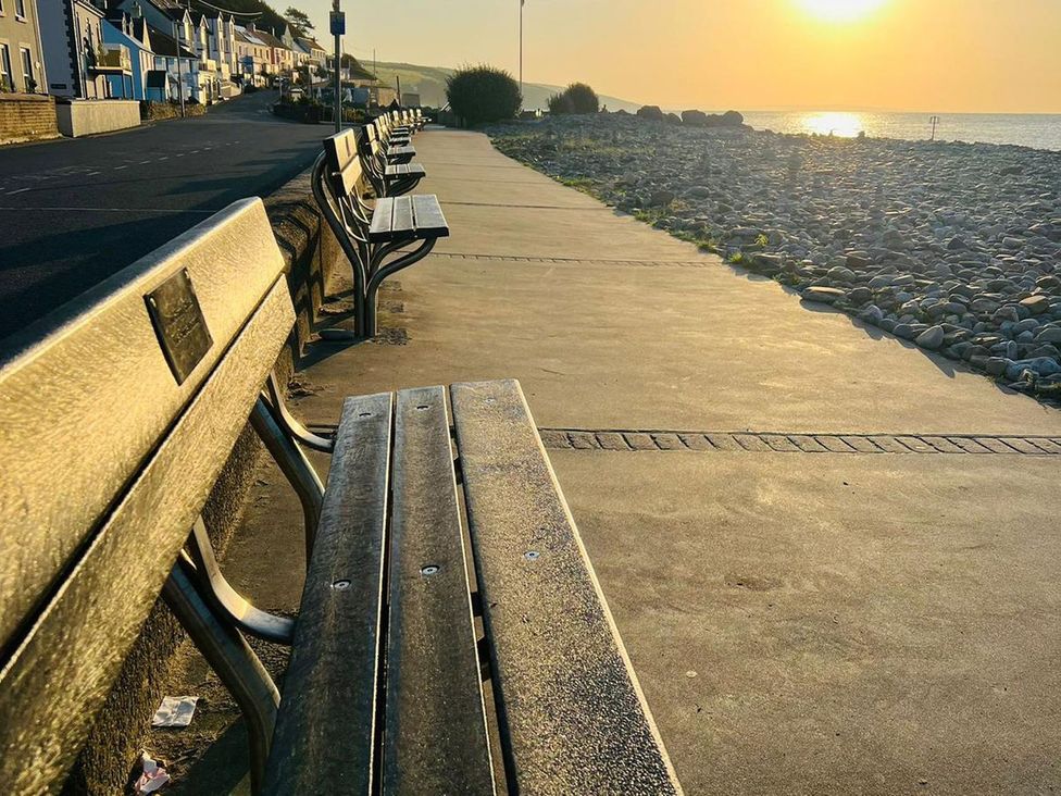 A row of benches along a pathway by the sea at The Cartwheel in Amroth