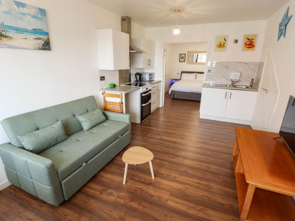 A living room with a sofa, coffee table, and kitchen at The Ocean House--- Sea Shell, Hunstanton