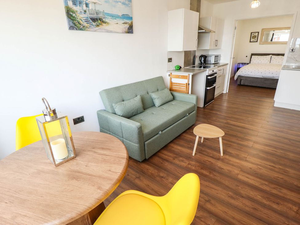 A living room with a sofa, table and kitchenette at The Ocean House--- Sea Shell in Hunstanton
