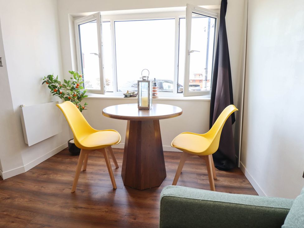 A dining room with a table and two yellow chairs at The Ocean House--- Sea Shell in Hunstanton