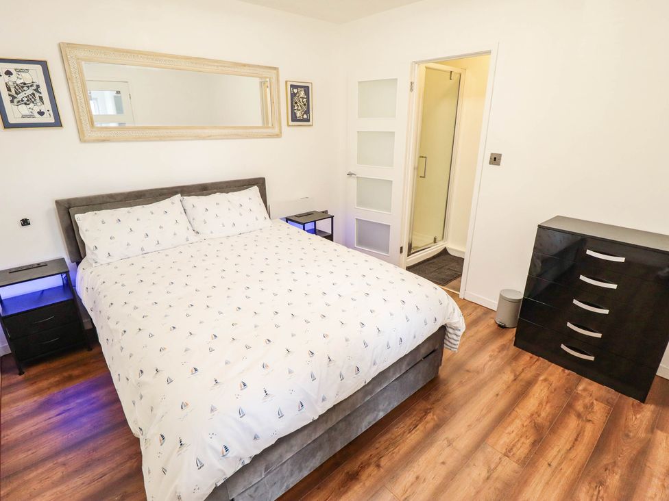 A bedroom with a double bed, nightstands, and a shower at The Ocean House--- Sea Shell in Hunstanton