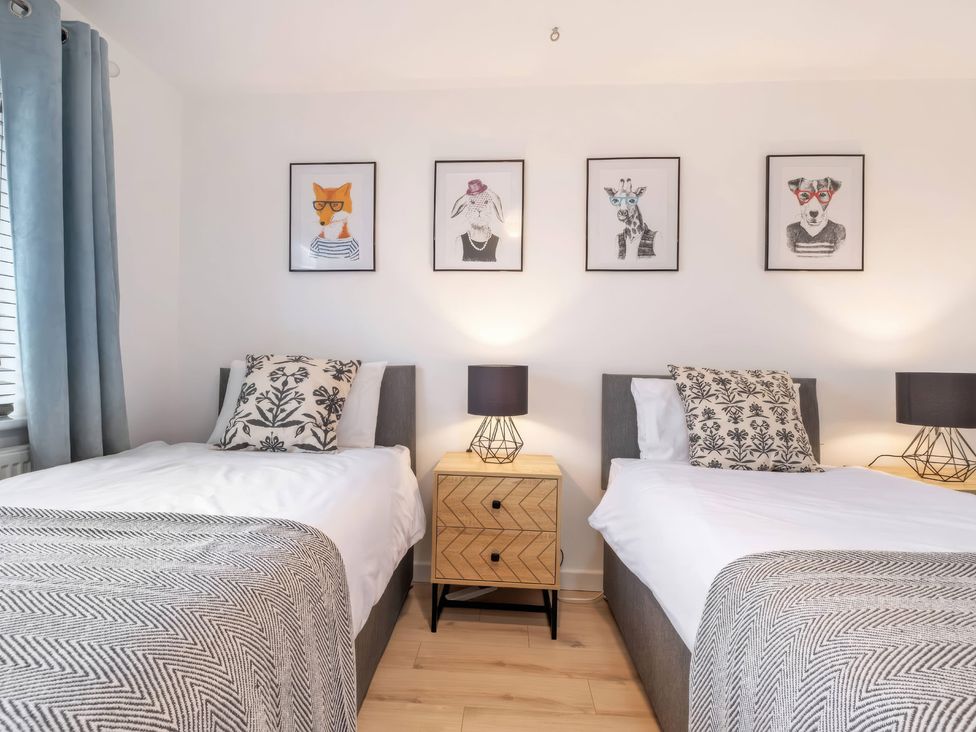 A bedroom with two single beds and artwork on the walls at TBC
