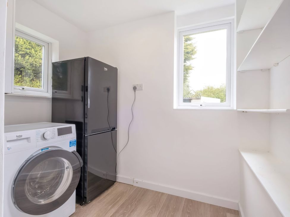 A laundry room with a washing machine and refrigerator at TBC
