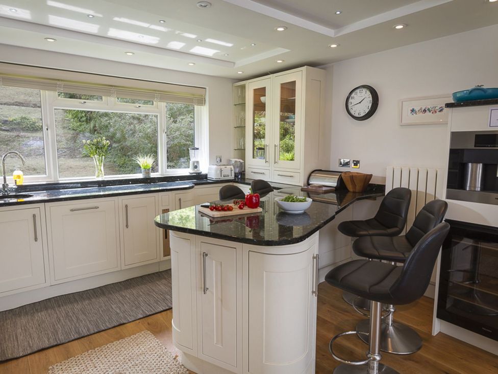 A kitchen with an island and bar stools at 6 Knowle Court Salcombe