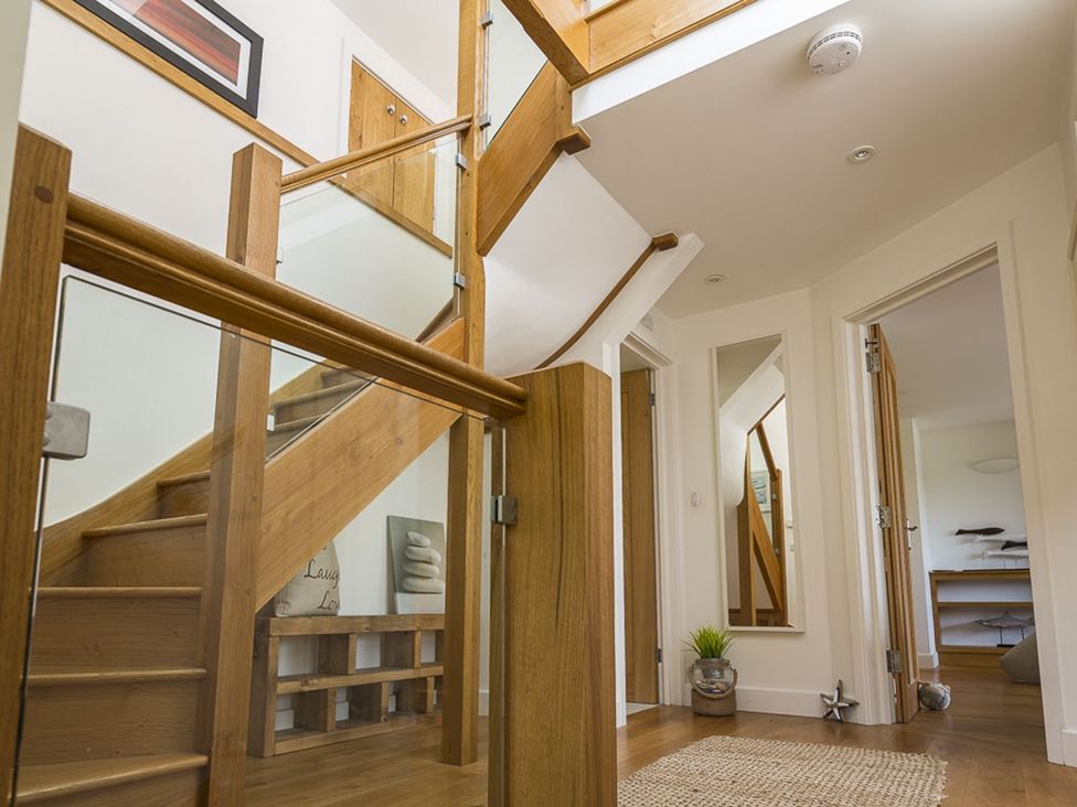 A hallway with a staircase and a mirror at 6 Knowle Court Salcombe