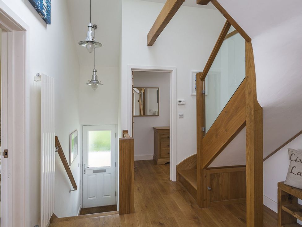 A hallway with a staircase and a door at 6 Knowle Court in Salcombe