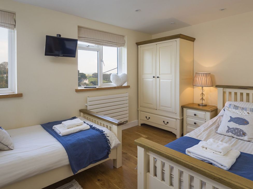 A bedroom with two beds, a wardrobe, and a television at 6 Knowle Court in Salcombe