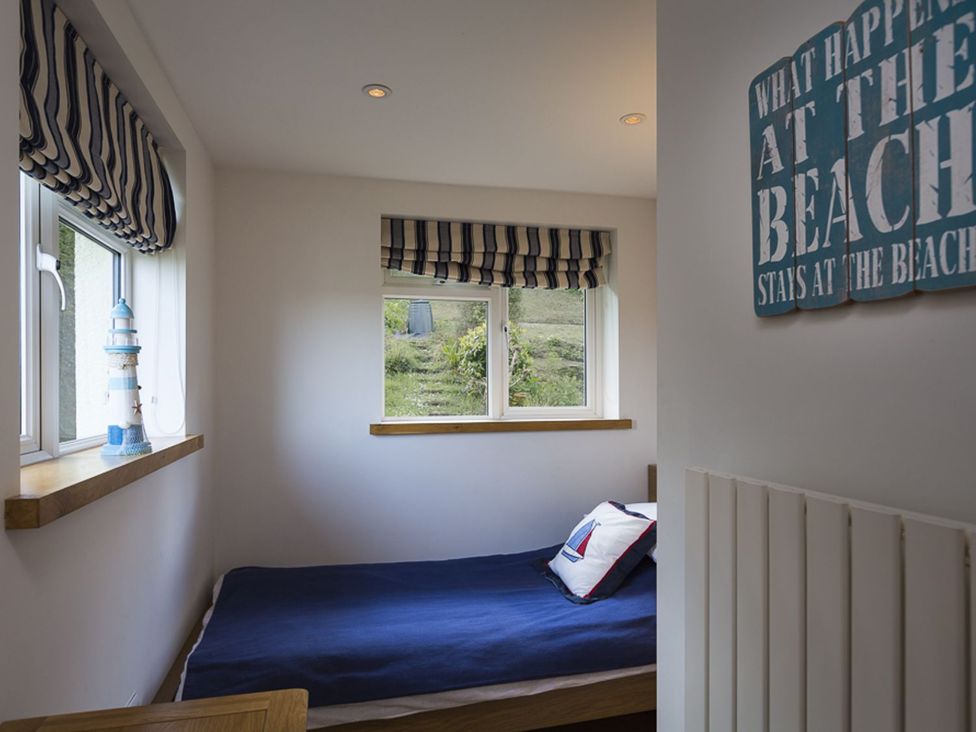 A bedroom with a bed and window decorations at 6 Knowle Court in Salcombe